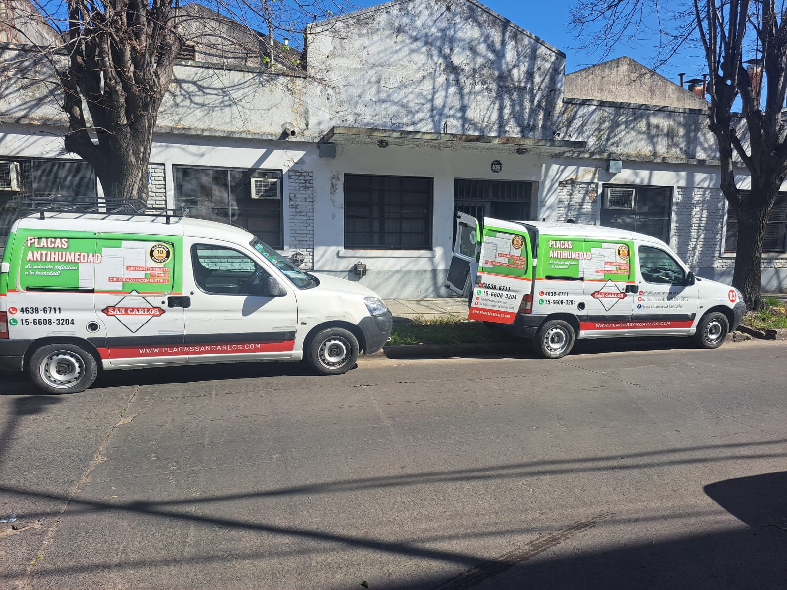 Flota propia Placas San Carlos — dos camionetas frente al local